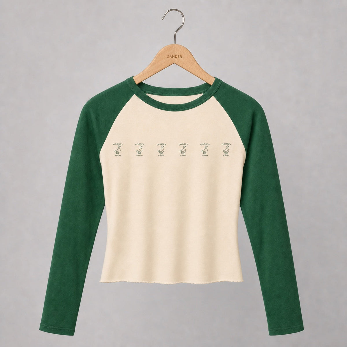 Women’s fitted hand-cropped cream and green Goosey baseball tee on a Gander wooden hanger